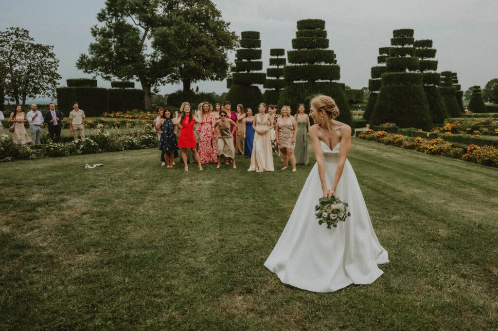 le lancé de bouquet de la mariée avec ses invitées en arrière plan lors d'un mariage au château de pizay